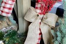 an oversized plaid candy cane wreath with a burlap bow and some berry branches is a lovely and bold decoration for outdoors and not only