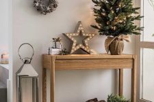 beautiful rustic Christmas decor with a tree in burlap, a basket with firewood, a marquee star light, vine wreaths with stars and pinecones