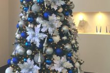 bright Christmas tree decor with lights, white fabric blooms, silver and blue ornaments plus gifts under the tree is a lovely idea