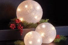 large snowball Christmas lights with berries and fir branches is a creative and cute decor idea for holidays