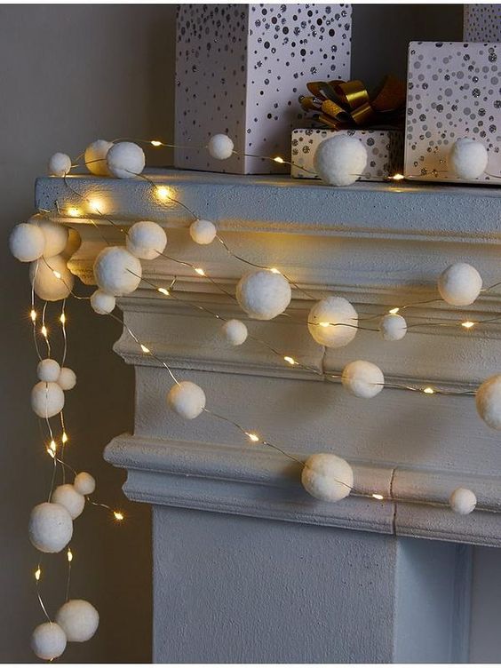 lights and snowball garlands on the mantel will add a holiday feel to your space at Christmas and you can craft them yourself