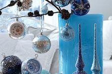 lovely blue and silver Christmas decor with a branch with ornaments, ornaments on the plate and some tree toppers