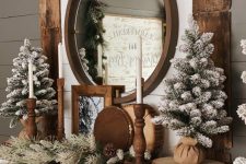 lovely rustic Christmas mantel with evergreens, flocked Christmas trees, wooden candleholders, pinecones and wood slices