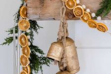 vintage bells, an evergreen garland, dried citrus slices, pompoms and stripes for an elegant vintage rustic mantel at Christmas