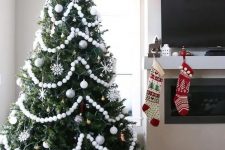a Christmas tree styled with white pompoms, white and silver ornaments and snowflakes is a chic and cool idea