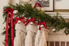 a beautiful evergreen Christmas garland with silver ornaments, red bows and white stockings is a cool decoration for any space