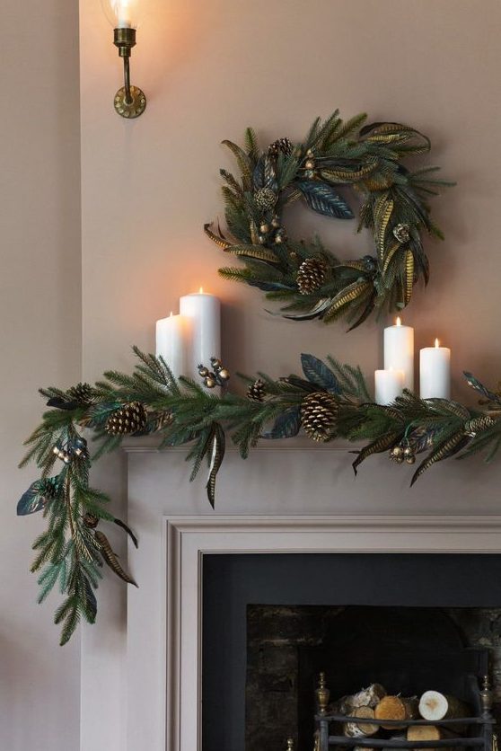 a chic evergreen garland with gilded touches, pinecones and a matching wreath over the mantel plus pillar candles