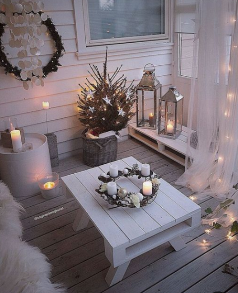 a cozy little winter balcony with shiplap furniture, faux fur, candles in candleholders and candle lanterns, a mini tree with stars and a wreath
