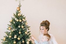 a glam Christmas tree with gold baubles and stars and a delicate gold snowflake tree topper that looks cool