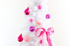 a gorgeous white Christmas tree decorated with bubblegum pink, fuchsia and purple ornaments and ribbons and topped with an oversized Christmas ornament in pink