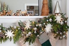 a lush and bright Christmas garland of evergreens, white snowflakes, pinecones, silver ornaments and white and green stockings