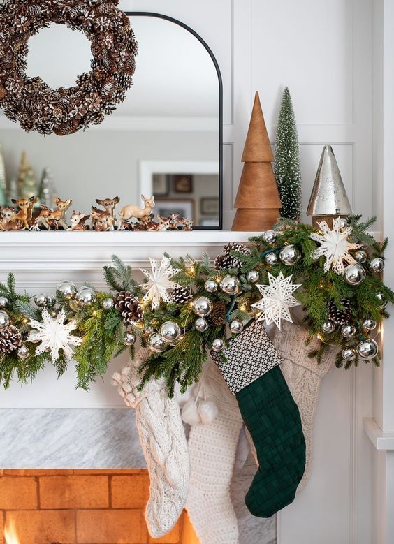 a lush and bright Christmas garland of evergreens, white snowflakes, pinecones, silver ornaments and white and green stockings
