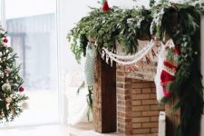 a lush and textural greenery garland on the mantel, white garlands and stockings hanging down from it