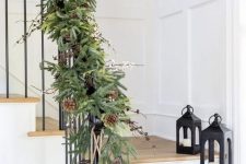 a lush evergreen garland with pinecones and berries plus large bells will make your staircase super festive