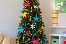 a shiny marquee star tree topper is a great solution for this colorful kids’ Christmas tree with letters and stars