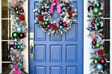 super bright Christmas front door decor with a silver garland with colorful ornaments, striped bows and a matching wreath plus colorfil gift boxes