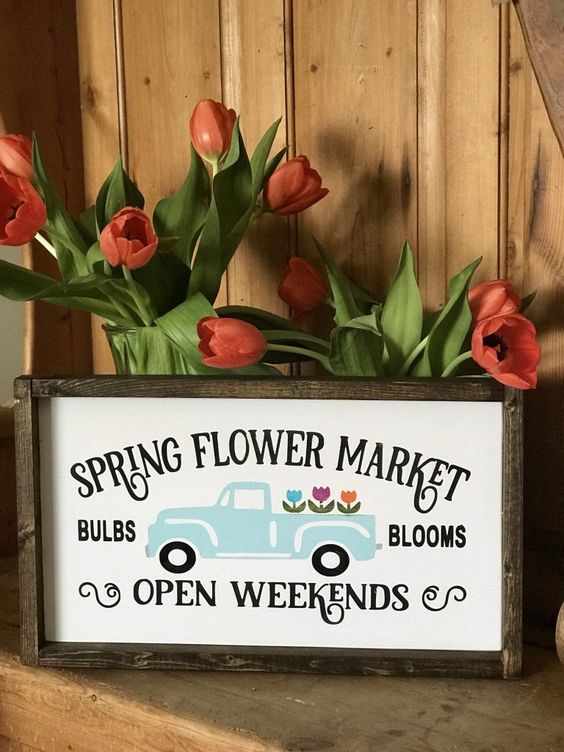 a bright and fun spring sign with a pastel truck and blooms and letters in a simple stained wooden frame