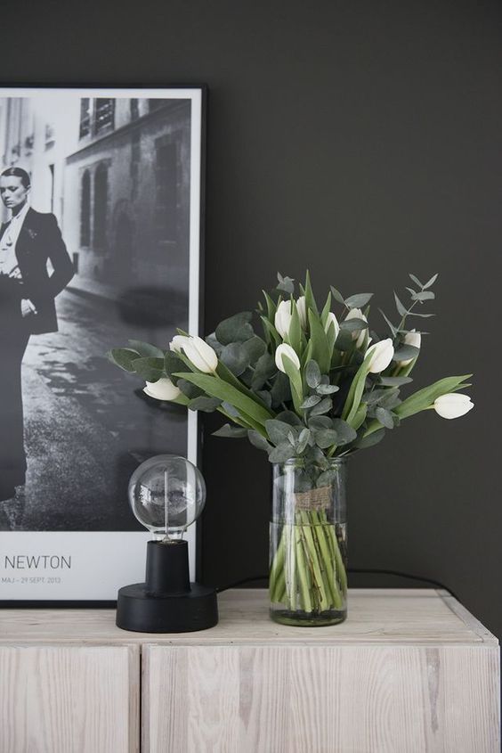 a chic and stylish spring flower arrangement of white tulips and eucalyptus in a clear vase is very modern