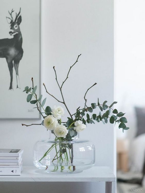 a clear vase with white ranunculus and eucalyptus and twigs is a lovely and fresh spring idea