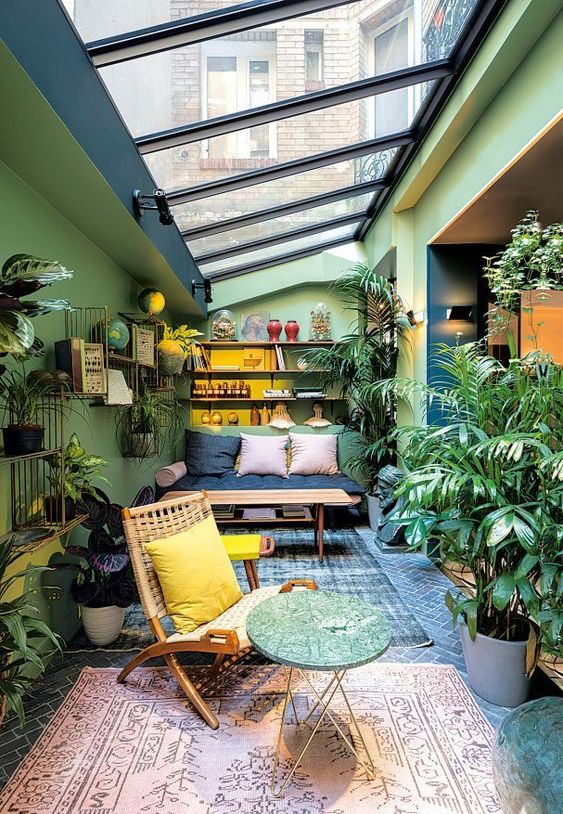 a colorful sunroom with green walls, bright furniture, potted greenery and blooms