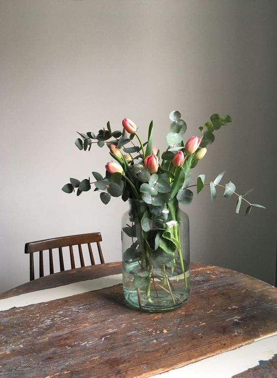 a large jar with pink tulips and fresh eucalyptus is a very lovely and cool spring flower arrangement you’ll enjoy
