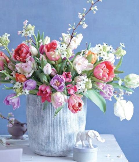 a large vase with colorful tulips and some white blooms is a gorgeous spring-inspired floral arrangement