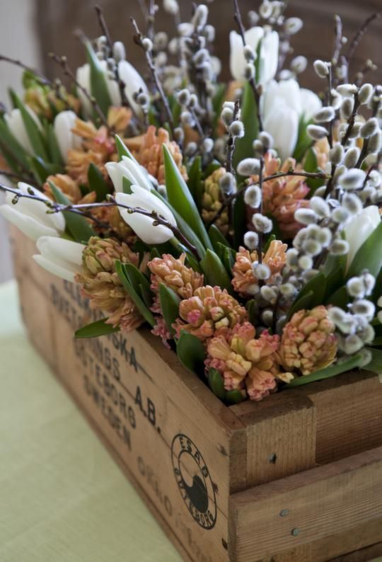 a lovely rustic spring floral arrangement of a wooden box, rust tulips, white ones, willow and leaves is amazing