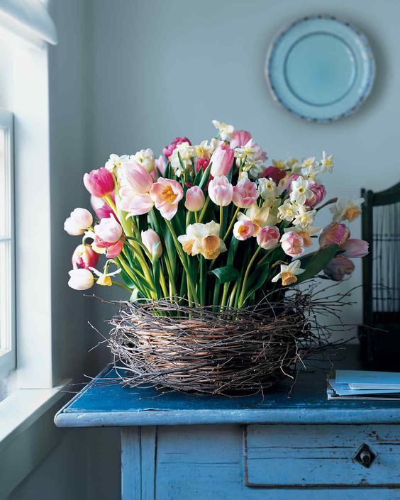 a nest with bright tulips and daffodils is a very pretty and cool spring arrangement or centerpiece for a rustic space