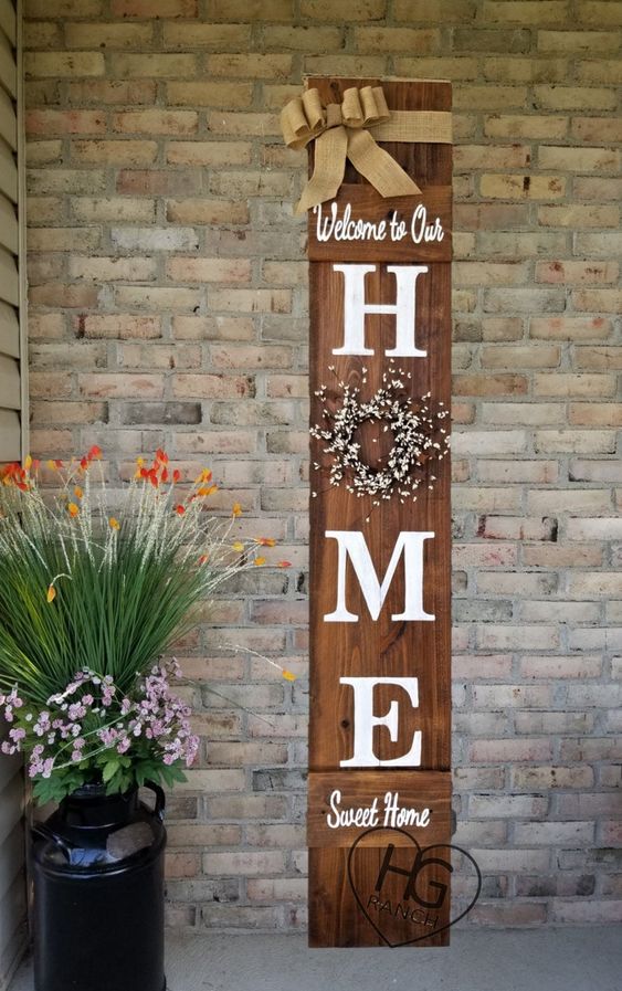 a rustic spring sign of a stained piece of wood, with a blooming wreath, a burlap ribbon and some letters