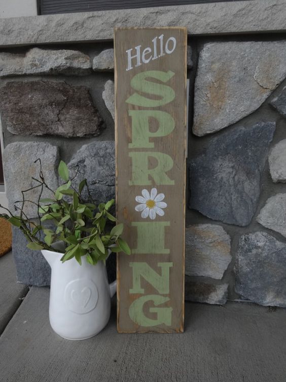 a rustic spring sign with green letters, a white bloom is a simple and easy idea for a rustic outdoor space