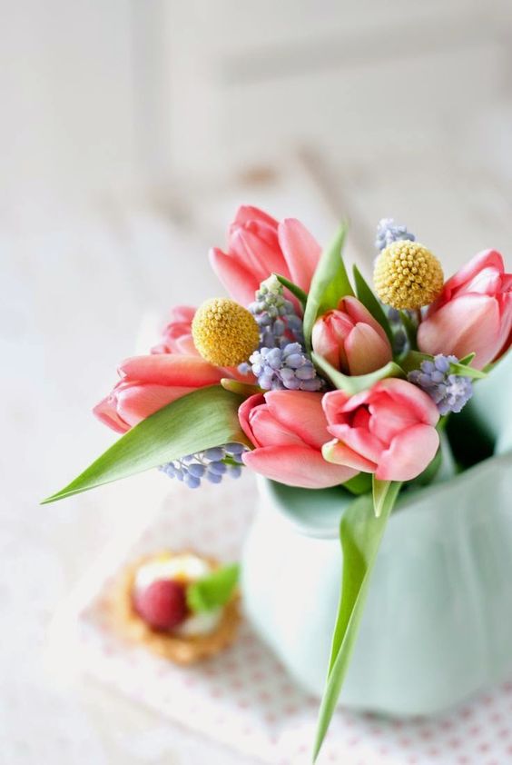 a simple and beautiful spring flower arrangement with blue, yellow and pink blooms and leaves is a chic idea