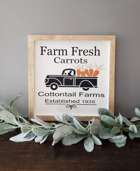 a small spring sign with a truck carrying carrots, with some letters and in a simple wooden frame