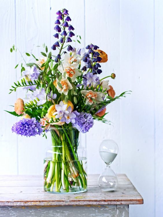 a super bright flower arrangement in purple, rust, yellow and peachy plus greenery is a bold spring decor idea