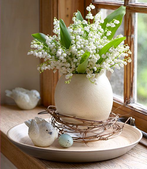a white porcelain vase with lily of the valley is a lovely spring arrangement with a gorgeous aroma at the same time