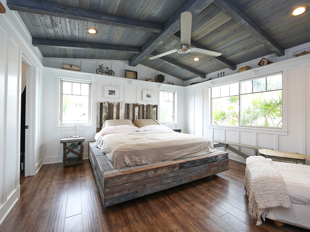 a farmhouse bedroom with white walls, a weathered wood ceiling, a weathered wood platform bed and a barnwood headboard  (Better Living SoCal)