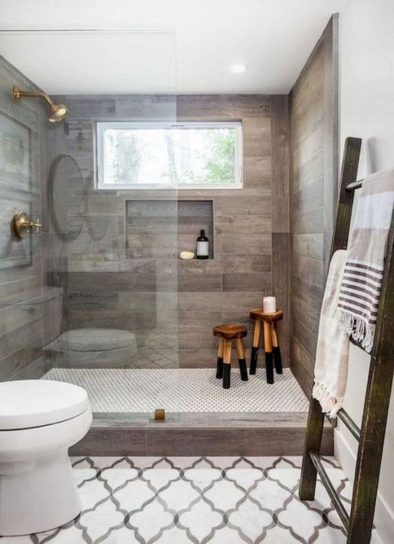 a contemporary farmhouse bathroom with mosaic tiles on the floor, wood-inspired tiles in the shower and a large ladder