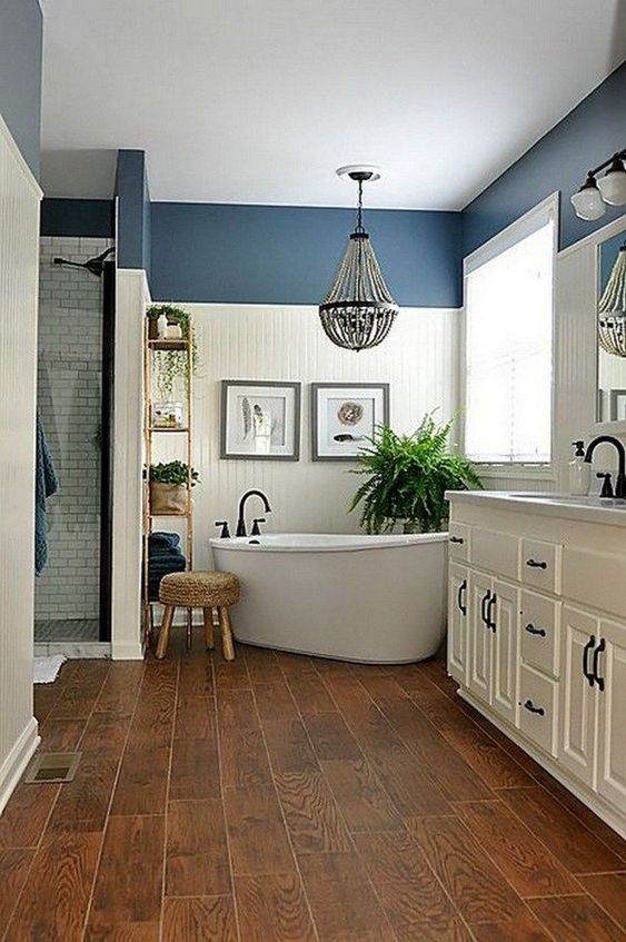 a farmhouse bathroom done in white and blue, with rich-stained wood, a bead chandelier and a vintage white vanity