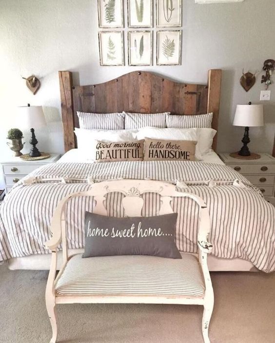 a farmhouse space with a gallery wall, a wooden bed, a vintage bench and striped bedding
