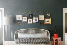 a gold photo rail with color family photos in mismatching frames hanging on it is a cool photo display idea