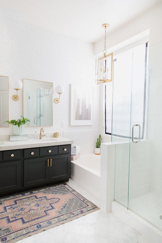 a light-filled farmhouse bathroom with a black vanity, gilded touches, white tiles and lamps