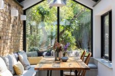 a modern sunroom that is a dining space, with a built-in bench, a dining table and vintage chairs is cool and cozy