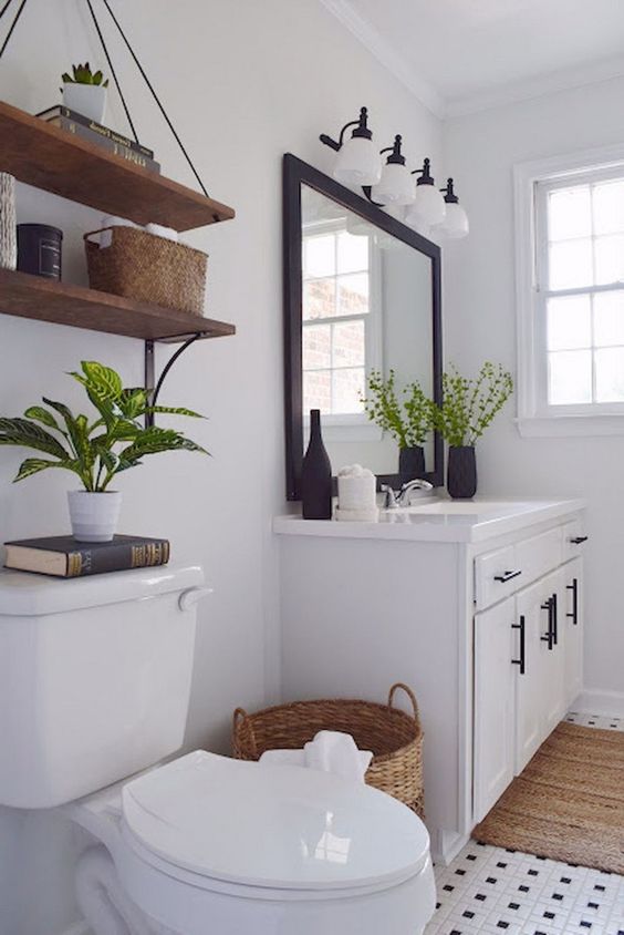 a modern white farmhouse bathroom with a modern vanity, a dark framed mirror, stained shelves and much light