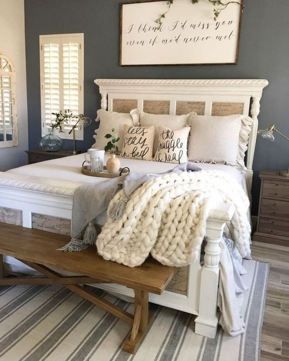 a stylish farmhouse bedroom with blue walls, striped textiles, knit and burlap accessories and a wooden bench