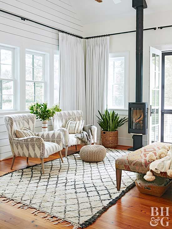 A stylish mid century modern rustic sunroom with pritned textiles, chic furniture, potted greenery and a hearth