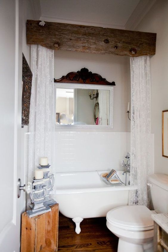a vintage farmhouse bathroom in white, with dark wooden touches for an accent, a tree stump side table and a clawfoot bathtub