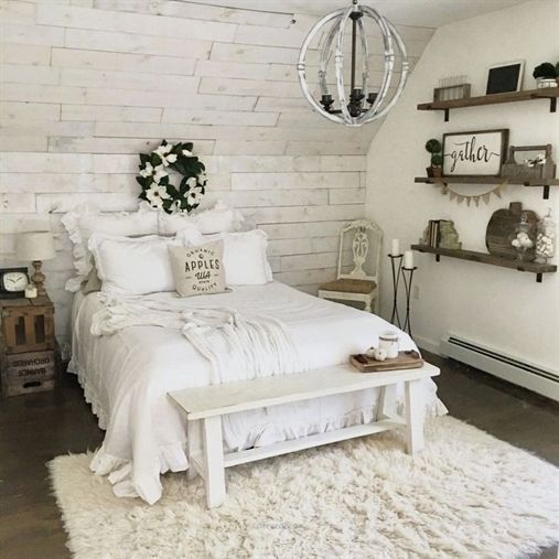 a vintage farmhouse bedroom of whitewashed wood, with elegant furniture and  a metal chandelier