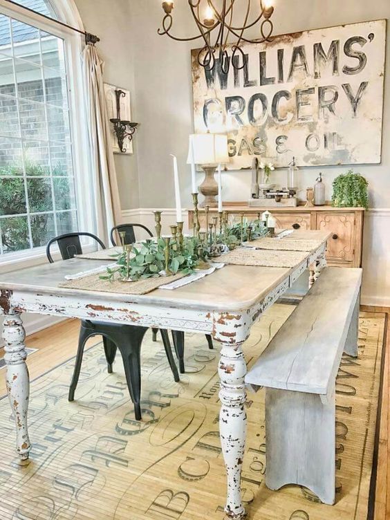 a vintage farmhouse dining space with a large sign, a wooden buffet, a shabby chic table and whitewashed bench
