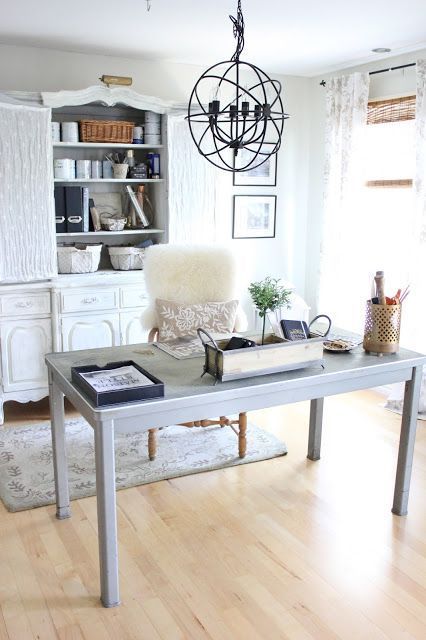 a vintage farmhouse home office with a large white storage unit, a neutral desk, a sphere chandelier and a fluffy fur chair
