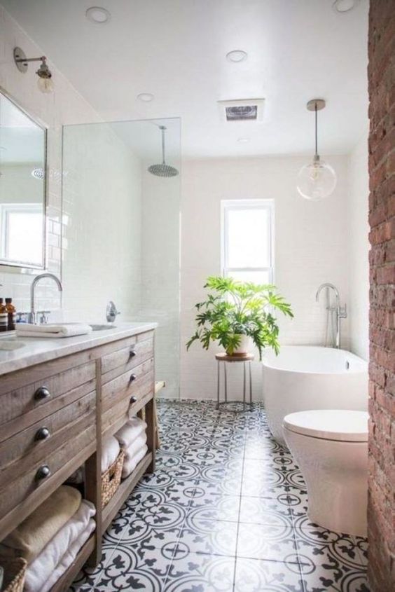 a welcoming farmhouse bathroom with a stained vanity, a brick wall, a mosaic tile floor and an oval tub