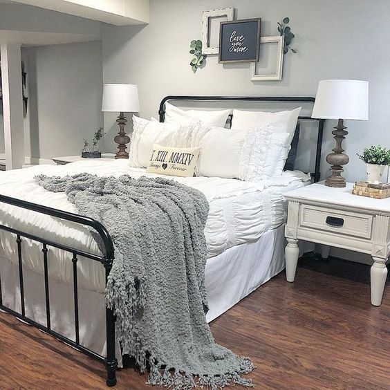 a welcoming farmhouse bedroom in neutrals and a black metal bed plus artworks over the bed